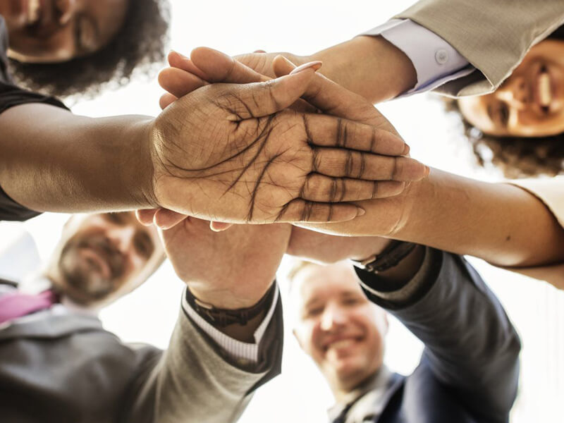 Business men and women with hands together in a circle